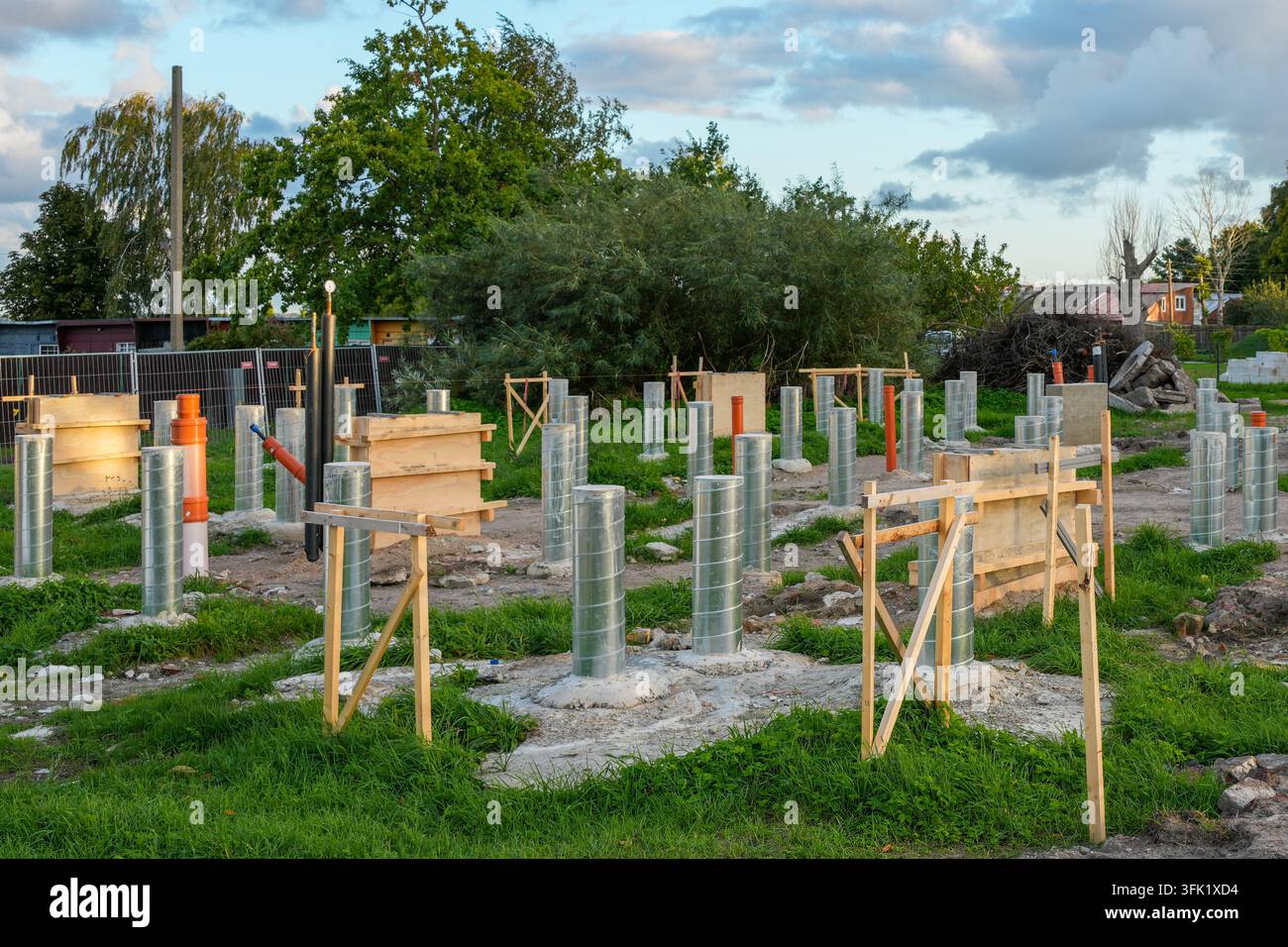 Fondazione a pali preparata con guaine metalliche, basi in cemento e tubi di servizio pronti per l'installazione di una casa modulare nel sito residenziale Foto Stock