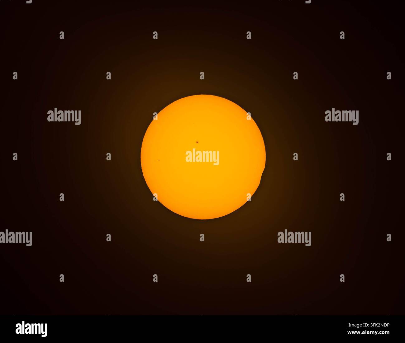 Un sole arancione luminoso è sospeso al centro di un vasto e oscuro vuoto. Foto Stock