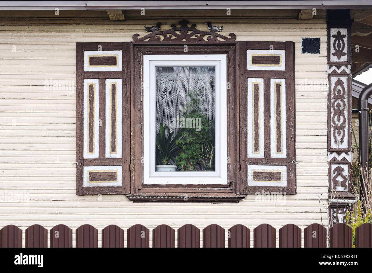 Finestra tradizionale in legno con persiane decorative. Sfondo architettonico per facciata rustica di design folk, vecchio edificio ed eredità rurale. Foto Stock