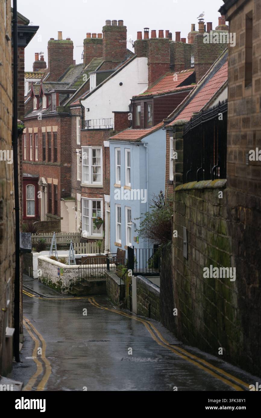 Una giornata piovosa di dicembre nella storica vecchia città di Whitby, dove vicoli stretti e affascinanti conducono verso l'iconica Abbazia e la Chiesa di Santa Maria. Foto Stock