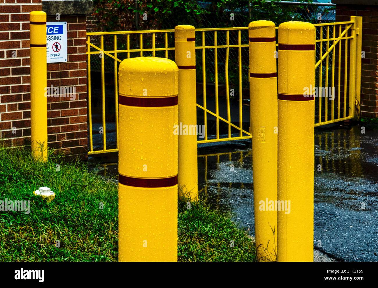 Coperture per pali Bollard in plastica giallo brillante dotate di strisce riflettenti rosso scuro o marrone. Foto Stock