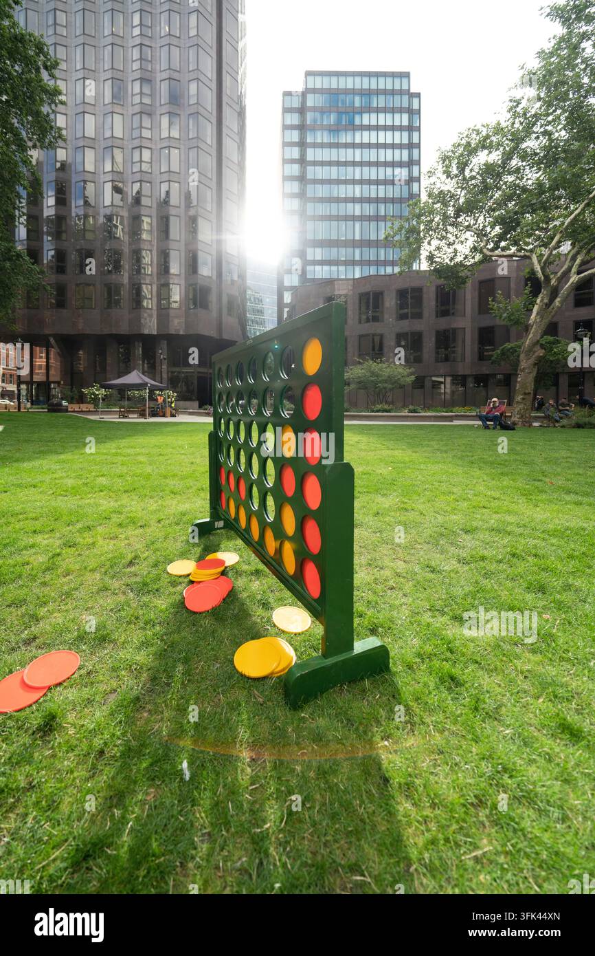 I visitatori si divertono con un gigantesco gioco di Connect Four ai Christchurch Gardens, un tranquillo parco urbano a Victoria, Londra. Foto Stock