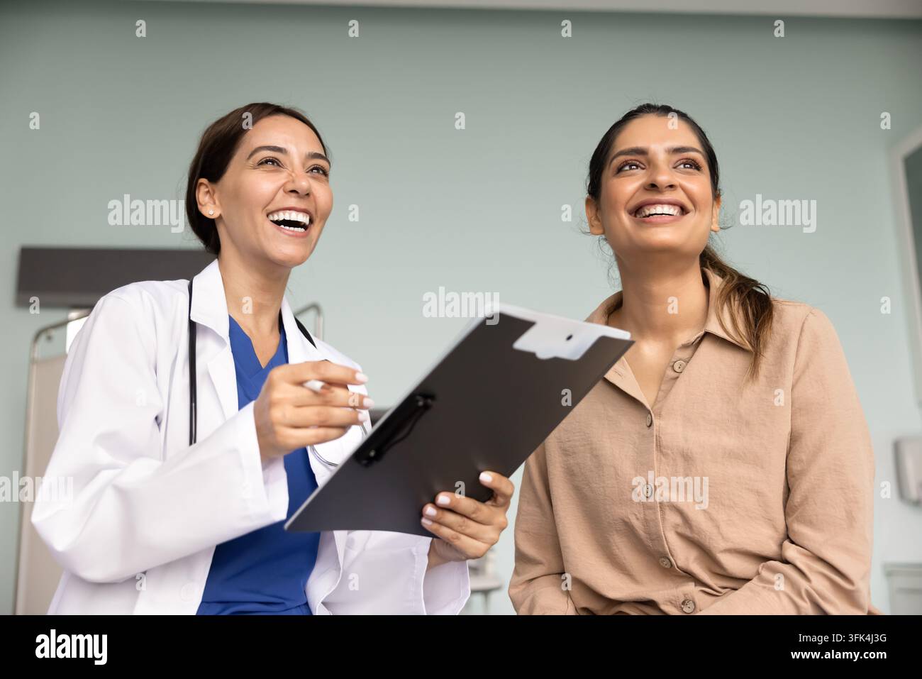 Medica allegra e giovane paziente che ridono durante la conversazione Foto Stock
