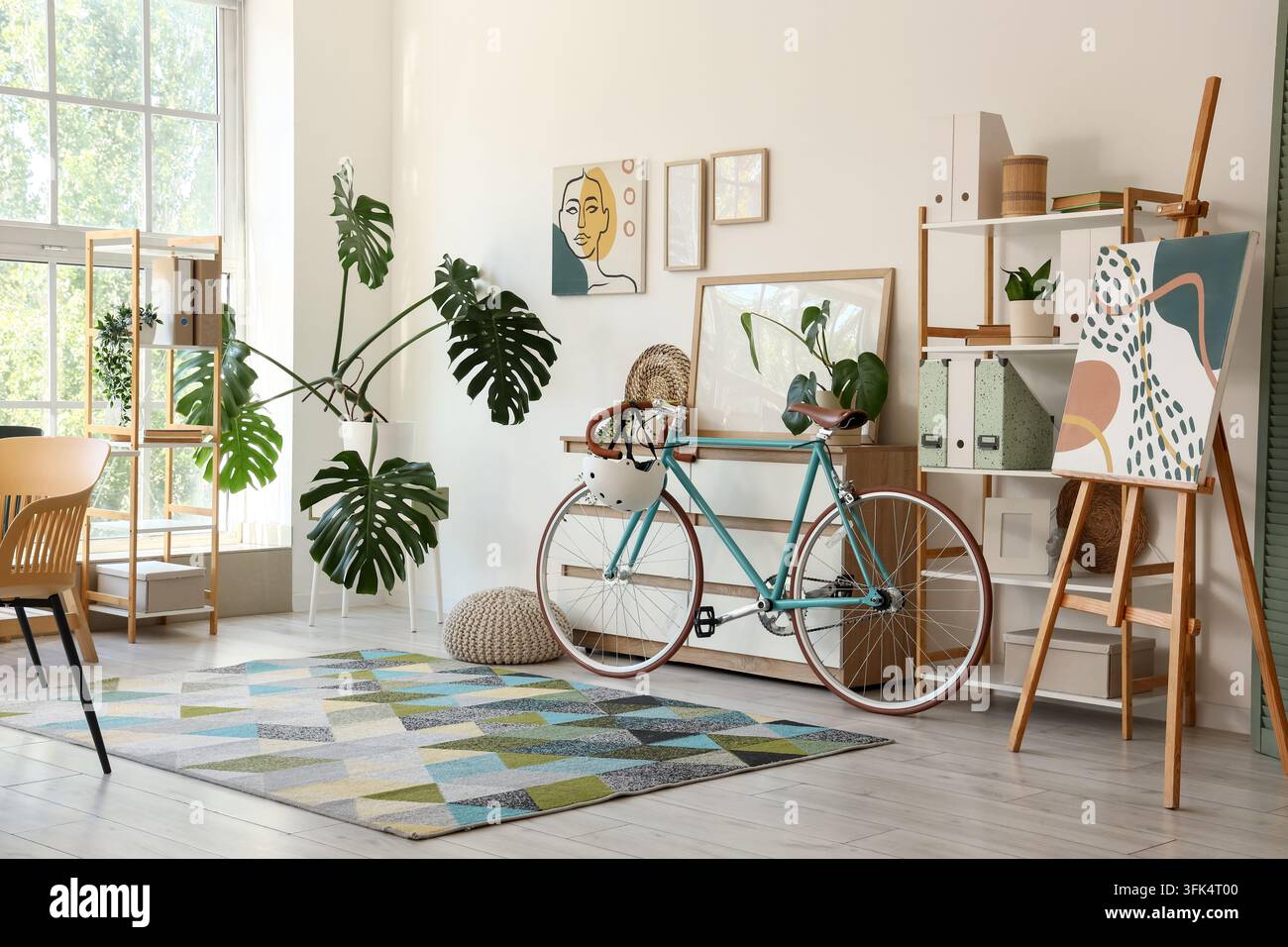 Stile di vita urbano sostenibile e ufficio domestico per il lavoro a distanza, bicicletta in un soggiorno moderno con piante d'appartamento e decorazioni artistiche per uno spazio creativo per freelance Foto Stock