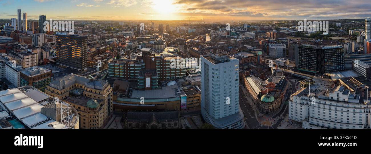Ampio panorama aereo verso est sul centro città di Leeds, che mostra il fitto paesaggio urbano e l'architettura dei tetti di fronte al sorgere del sole Foto Stock