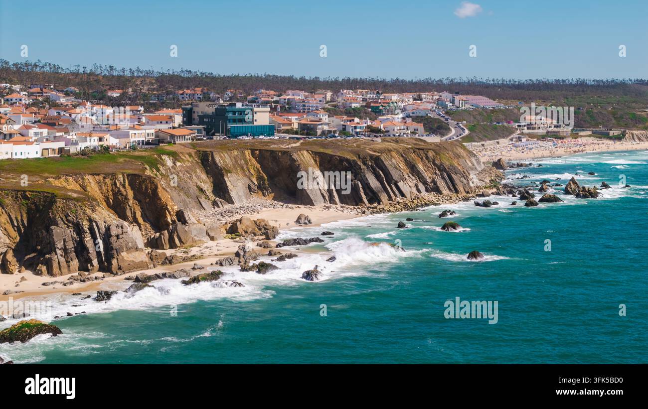 Veduta aerea di un villaggio costiero sopra scogliere frastagliate, insenature sabbiose, rocce e onde turchesi dell'oceano. Foto Stock