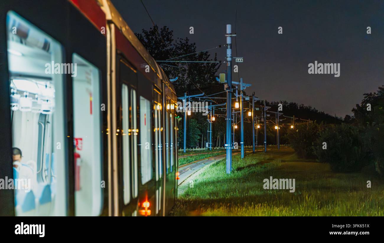 Tram che viaggiano di notte a Pechino con il paesaggio urbano lungo il percorso Foto Stock