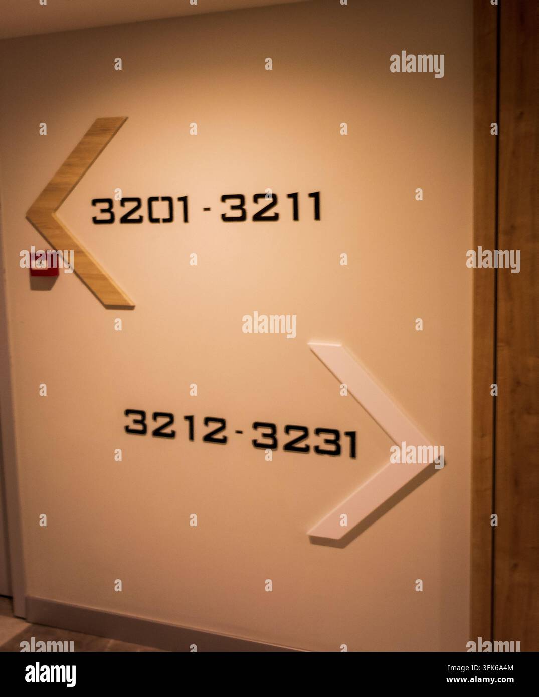 Segnale stradale del corridoio di un hotel moderno con frecce in legno che indicano le direzioni dei numeri delle stanze. Foto Stock