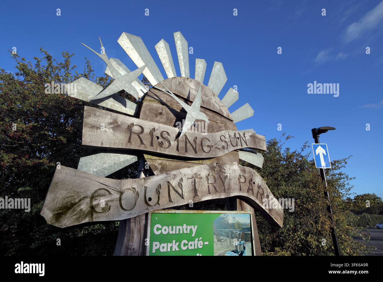 Insegna all'ingresso del parco nazionale Rising Sun, Whitley Rd, Benton, Newcastle upon Tyne. Un cartello in legno con raggi di sole metallici. Foto Stock