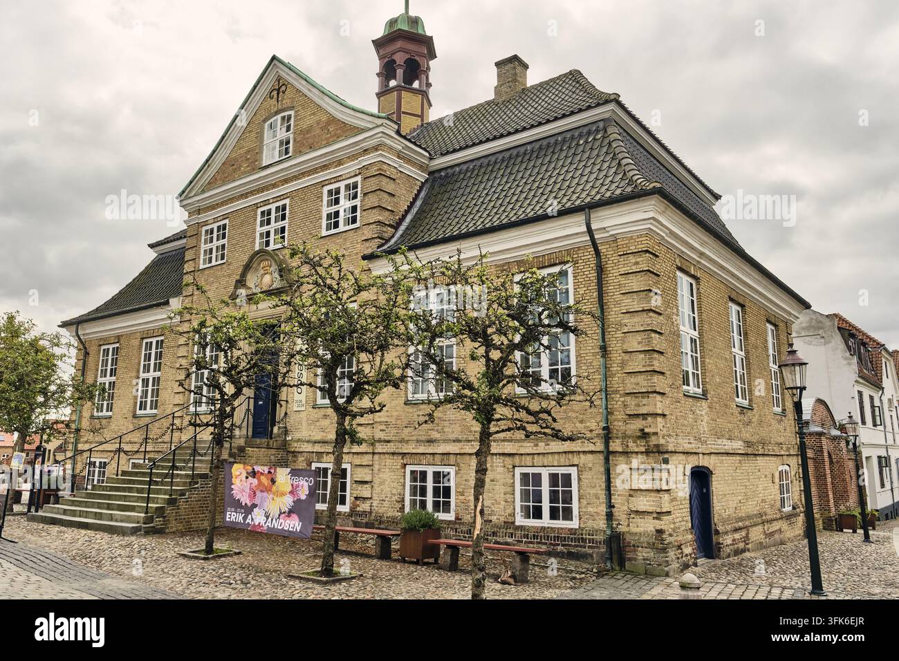 Viborg, Danimarca - 07 agosto 2026: Vista del museo Skovgaard, un edificio storico in mattoni gialli con un tetto prominente e piccoli alberi davanti sotto un cl Foto Stock