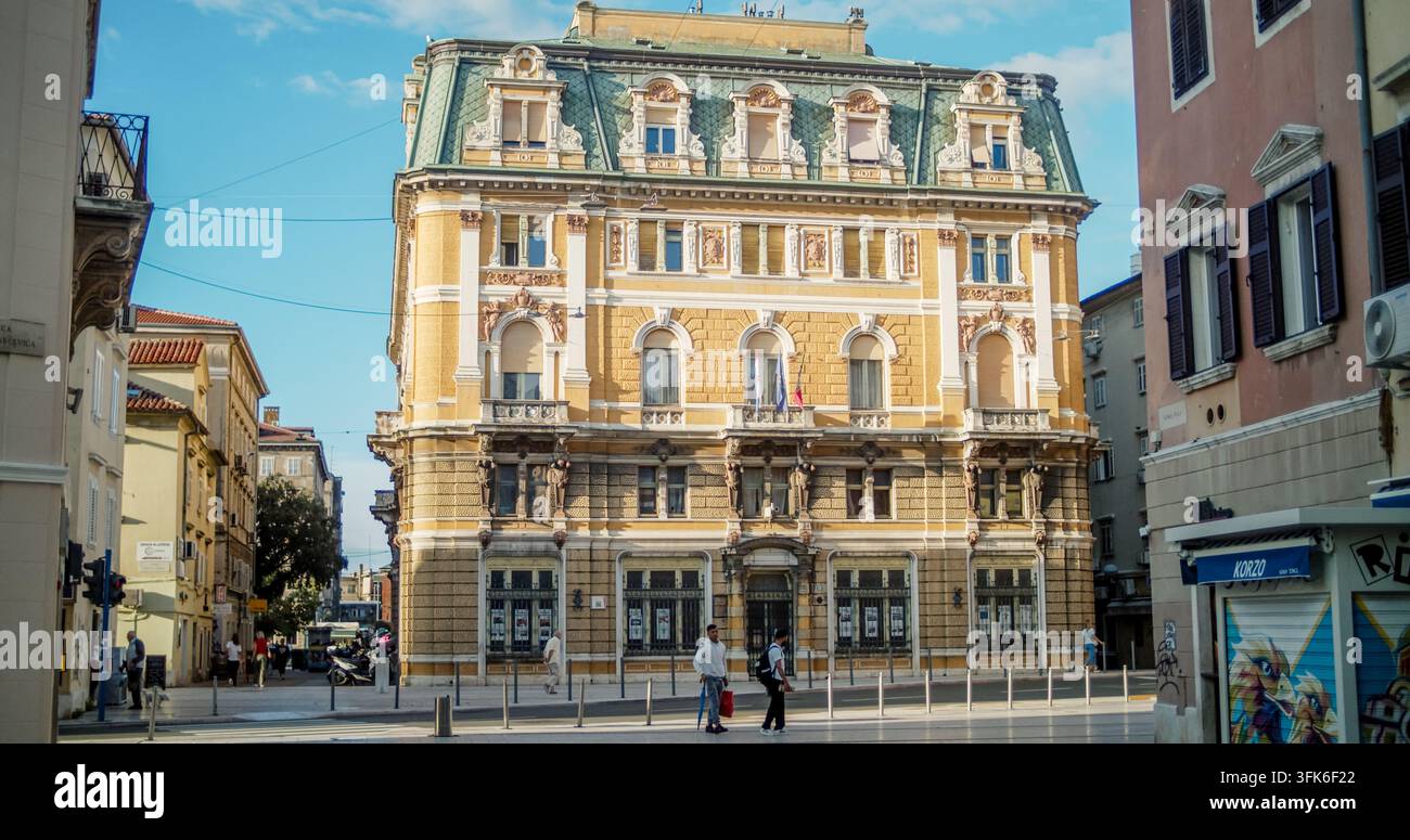 Rijeka, Croazia - 19 settembre 2026: Vista di un edificio storico con facciata gialla ornata e tetto verde, caratterizzato da intagli architettonici dettagliati Foto Stock