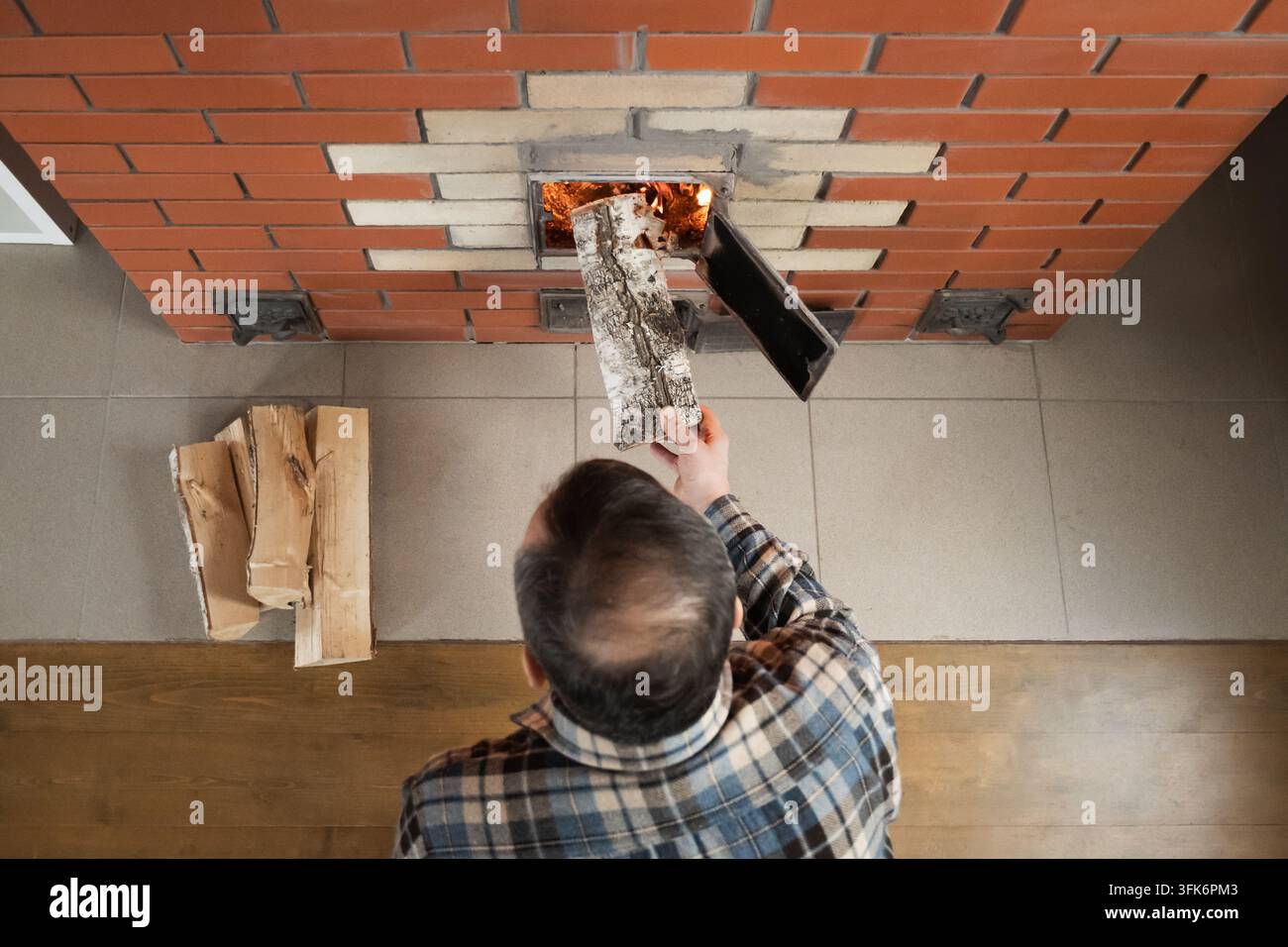 Uomo che mette legna da ardere in una stufa a legna Foto Stock