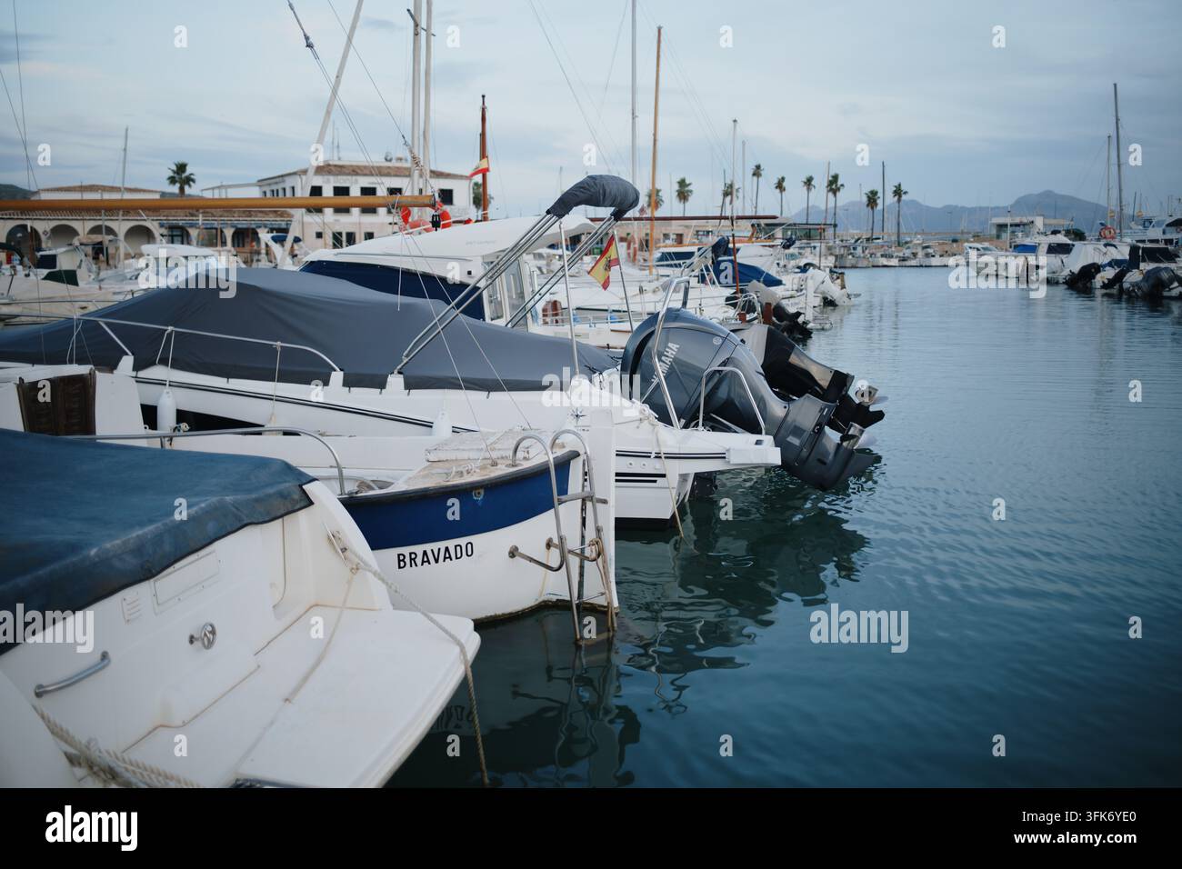 Port de Pollenca, Spagna – 05 gennaio 2025: Vista delle barche ormeggiate nel porticciolo con acqua calma e edifici sullo sfondo. Foto Stock
