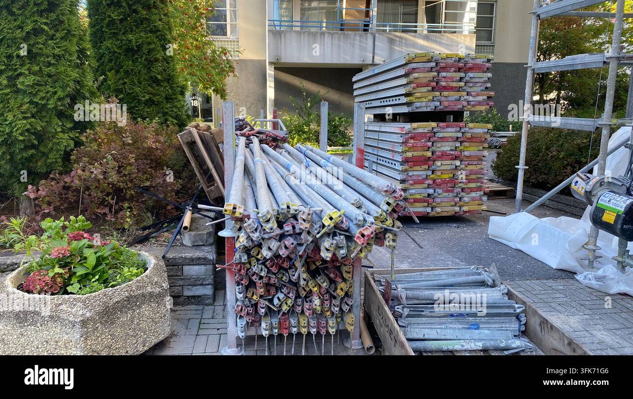 Materiali per impalcature e attrezzature di costruzione metallica accatastate all'esterno di un edificio residenziale durante i lavori di ristrutturazione Foto Stock