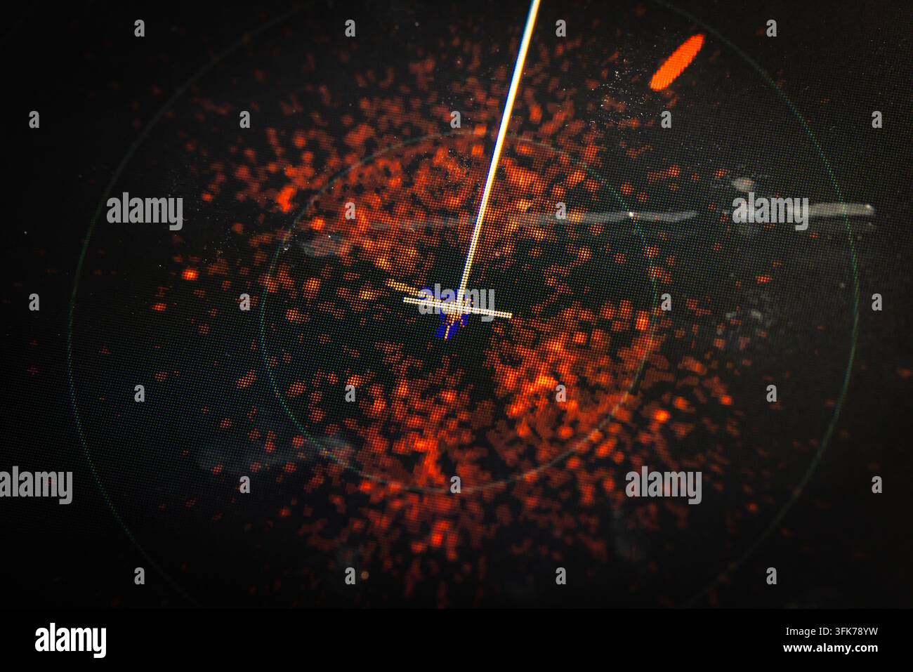 Vista ravvicinata di uno schermo di navigazione radar che mostra ritorni di segnale rossi e una linea di scansione luminosa che segue bersagli aerei, che trasmette sorveglianza, marit Foto Stock