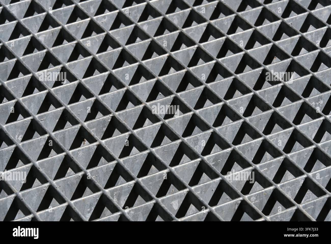 Modello astratto di luce e ombra su griglia metallica con motivi geometrici di triangoli Foto Stock