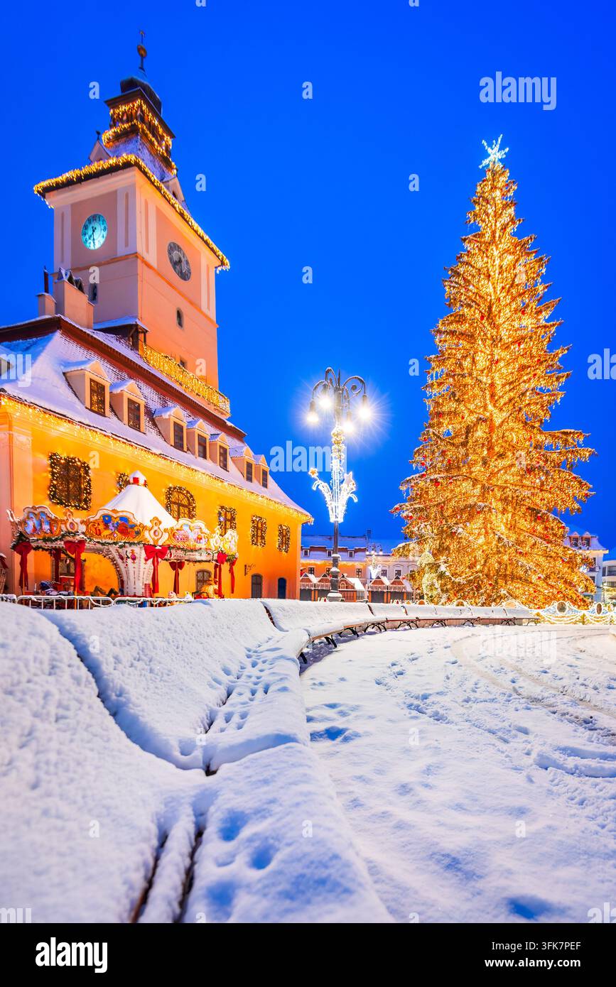 Scena innevata del mercato natalizio di Brasov, della Casa del Consiglio e dell'enorme albero di Natale. Foto Stock