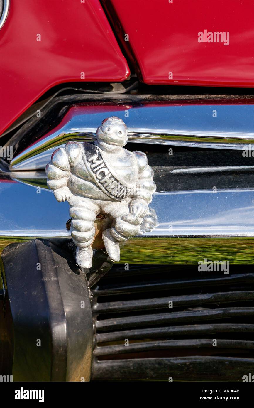 Maschera vintage di Michelin Man Bibendum montata sulla parte anteriore di un veicolo rosso Foto Stock