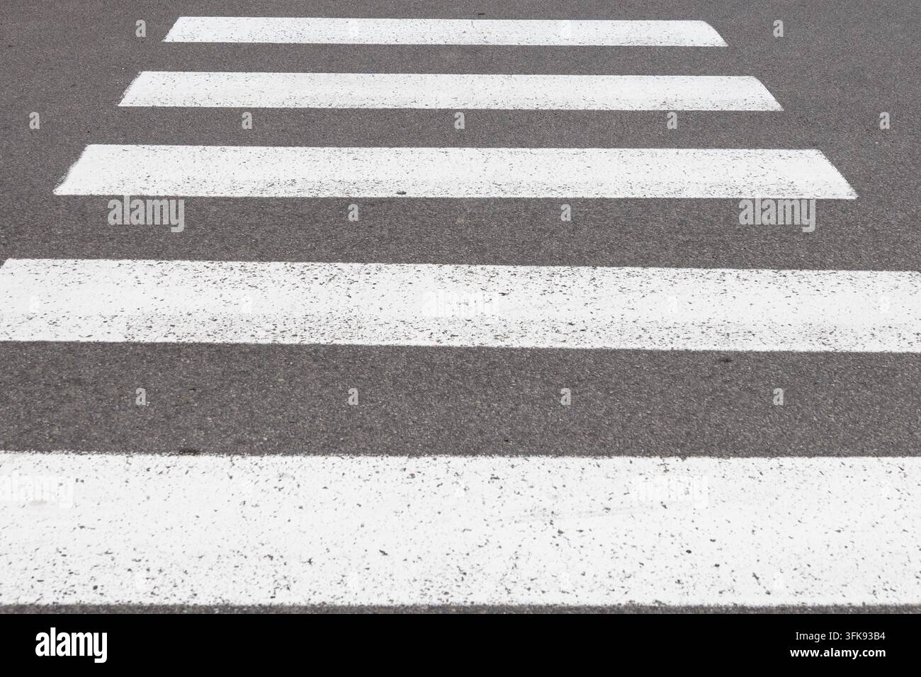 Strisce bianche di attraversamento pedonale su strada asfaltata scura Foto Stock