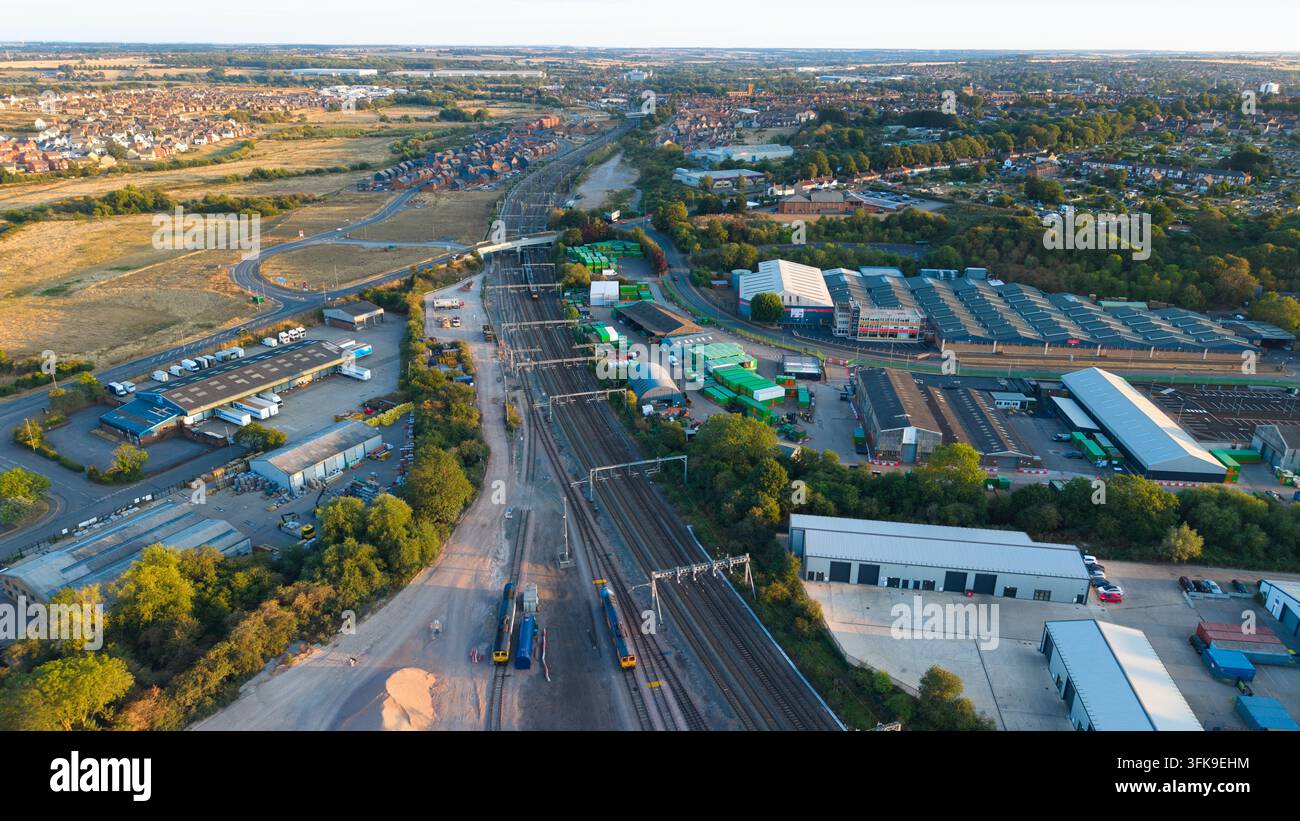 Vista aerea del terminal merci di Wellingborough con binari ferroviari, magazzini industriali e strutture di stoccaggio sotto la luce del tramonto a Wellin Foto Stock