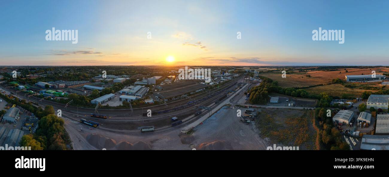 Vista aerea del terminal merci delle aree di stoccaggio di Wellingborough con binari ferroviari, edifici industriali e paesaggio sotto la luce del tramonto a Wellingborough Foto Stock