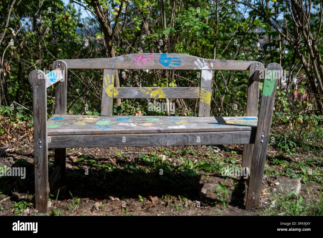 Impronte di mani colorate sul vecchio legno di una panchina, in piedi all'aperto che offre spazio per riposare al sole. Foto Stock