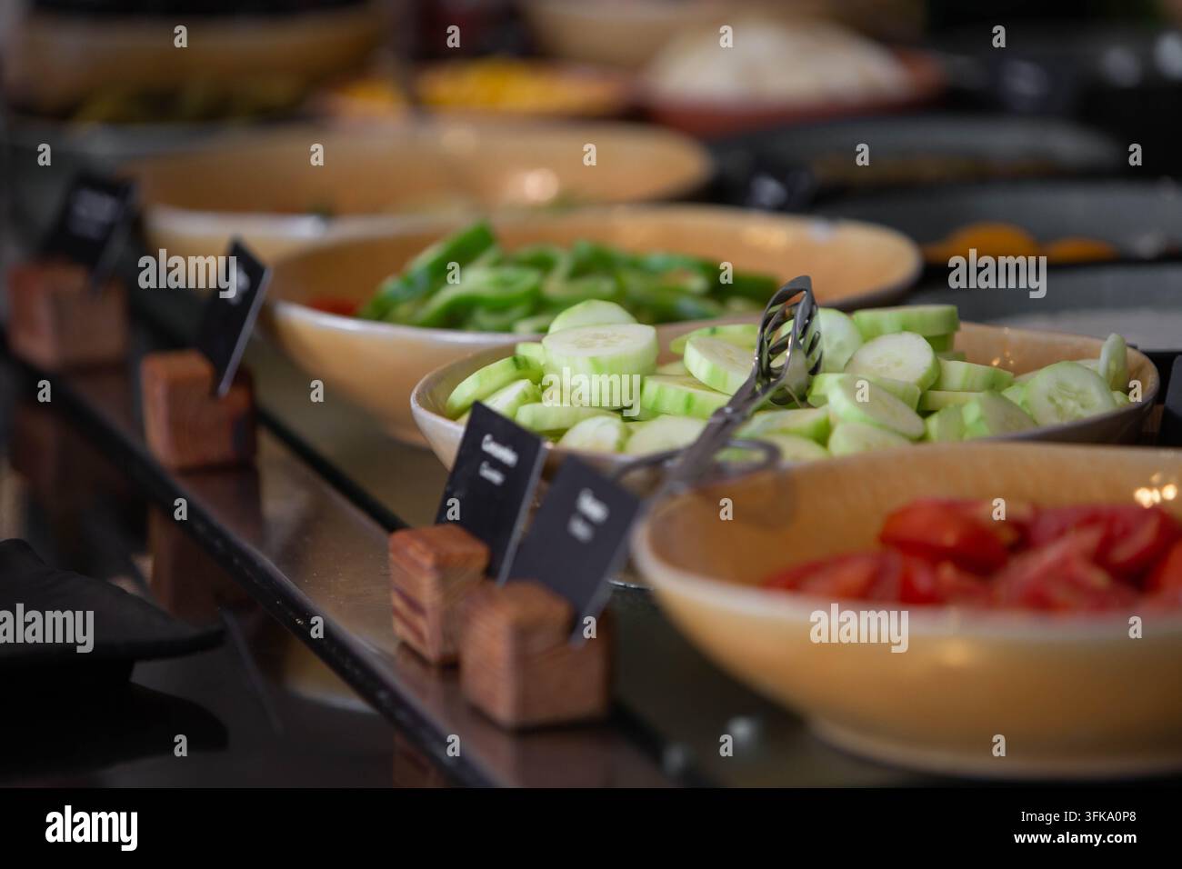 Bar di insalata di verdure fresche al buffet della colazione dell'hotel con cetrioli e pomodori affettati. Bar di insalata self-service salutare con cetrioli freschi affettati Foto Stock