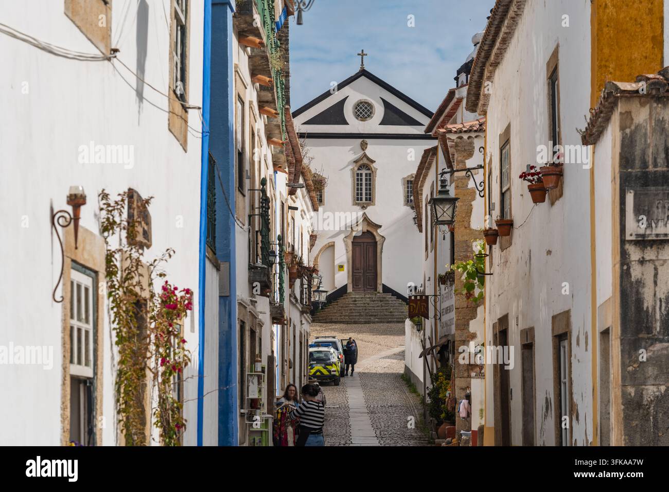 Obidos, Portogallo - 13 maggio 2026: Vista di una stretta strada acciottolata nella città storica di Obidos, con edifici tradizionali imbiancati, flusso Foto Stock