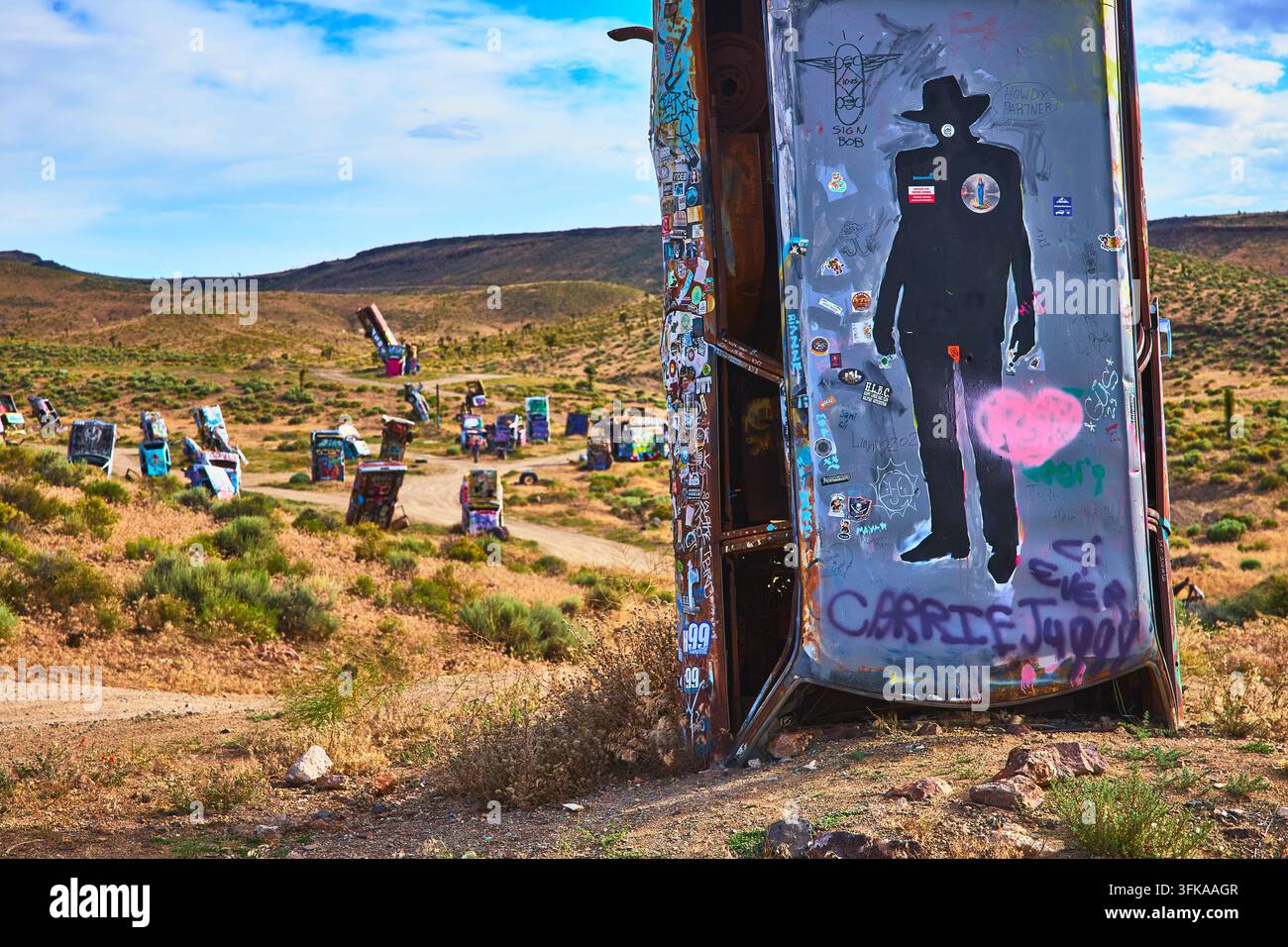 Veicoli abbandonati adornati di graffiti vivaci si ergono in piedi nella Foresta Internazionale delle Auto fuori Goldfield, Nevada. Il paesaggio arido e striki Foto Stock