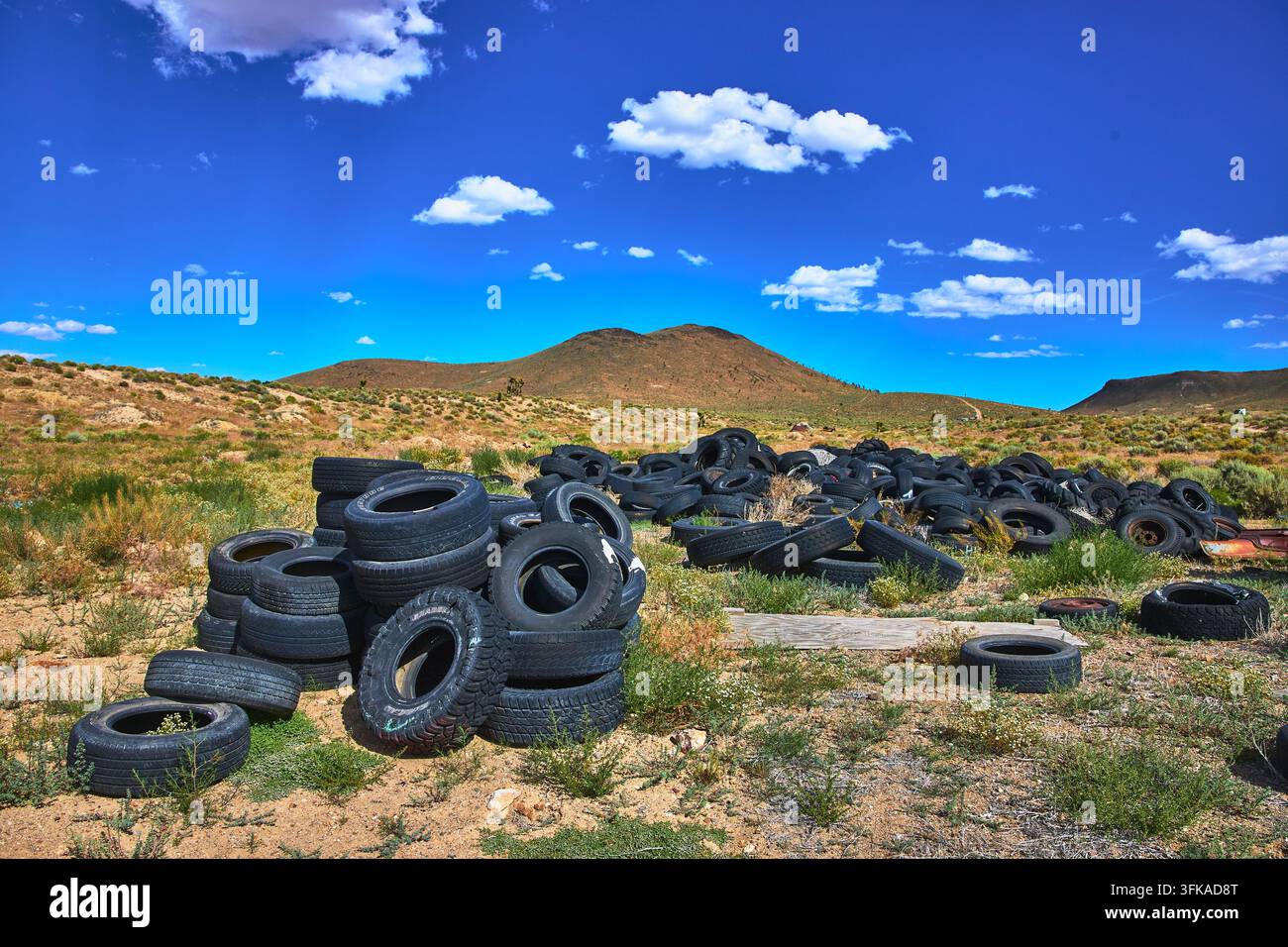 Gomme abbandonate nel deserto del Nevada con colline lontane e cielo blu Foto Stock