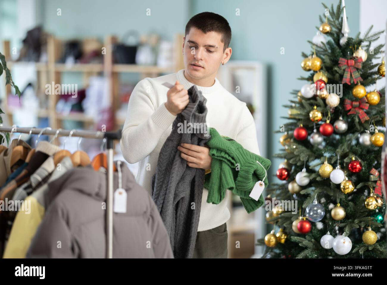 In negozio, un cliente sceglie il colore e lo stile di un maglione invernale. Creazione di un guardaroba capsule. Abiti casual pratici. Promozione vendite, trucco di marketing Foto Stock