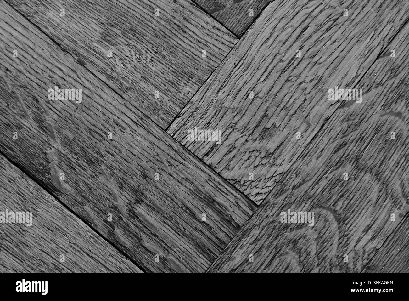 Vista ravvicinata di assi di legno grigie consumate che si incrociano diagonalmente, con venature pronunciate, nodi, graffi, giunture e una texture invecchiata varia Foto Stock