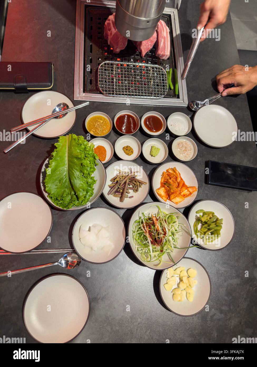 Tavolo barbecue coreano con maiale grigliato e contorni tradizionali Foto Stock