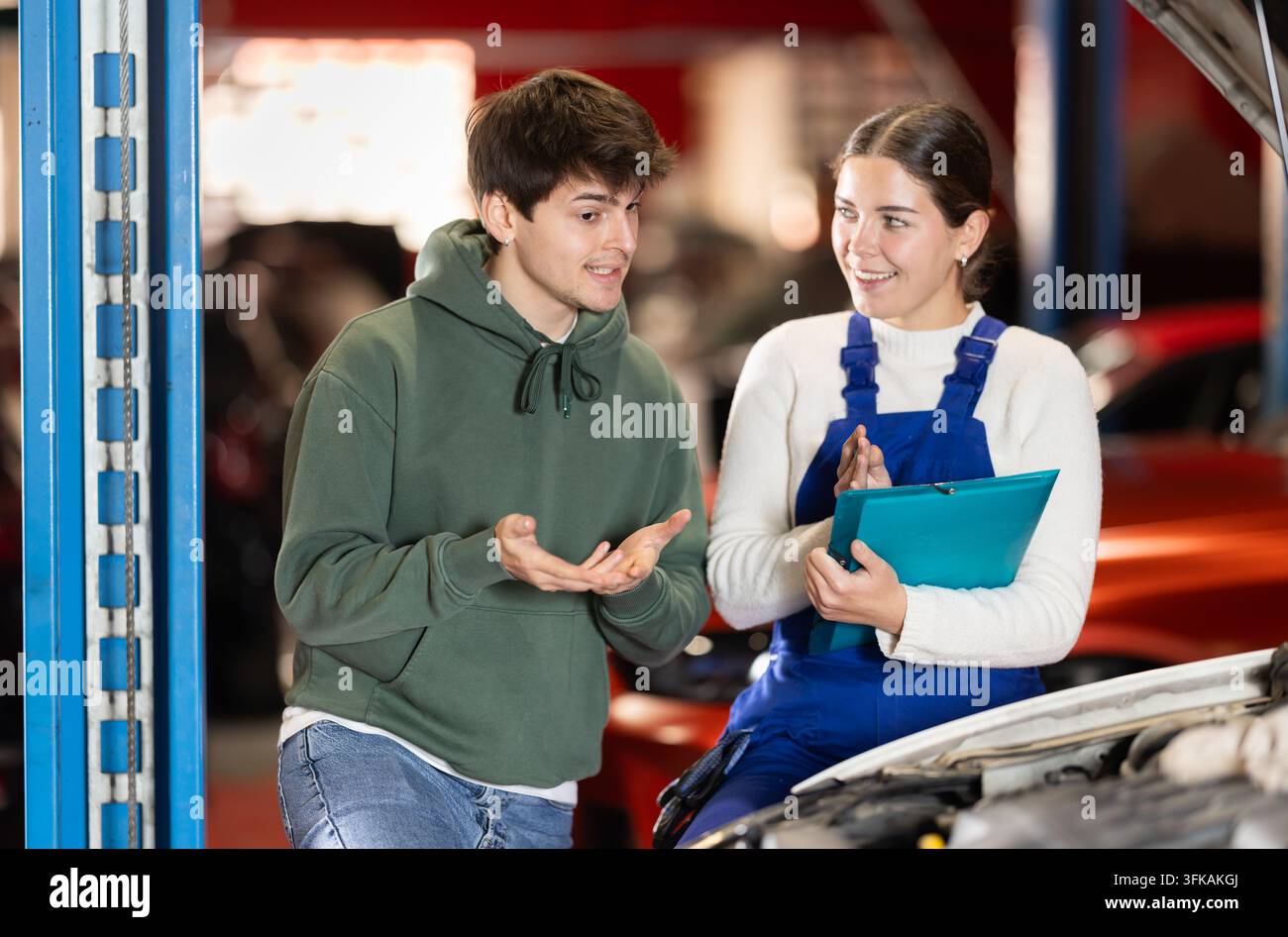 un cliente maschio si consulta con un meccanico per riparare un'auto Foto Stock