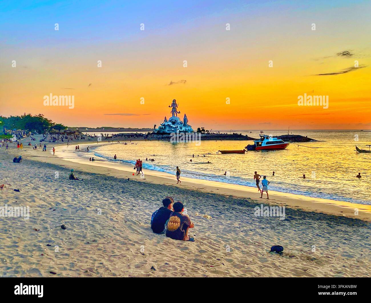Visitatori che si rilassano e camminano lungo la riva al tramonto su Jerman Beach, Kuta, Bali, Indonesia, il 12 aprile 2026. Foto Stock
