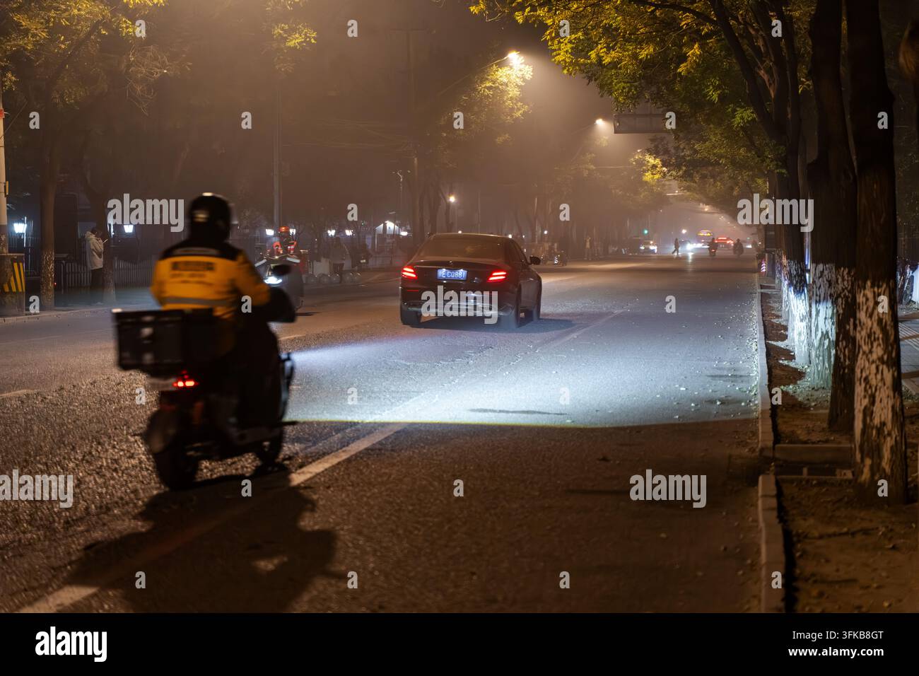 Corriere di consegna che lavora in una strada urbana nebbiosa di notte, documentario sui lavoratori della prima linea Foto Stock