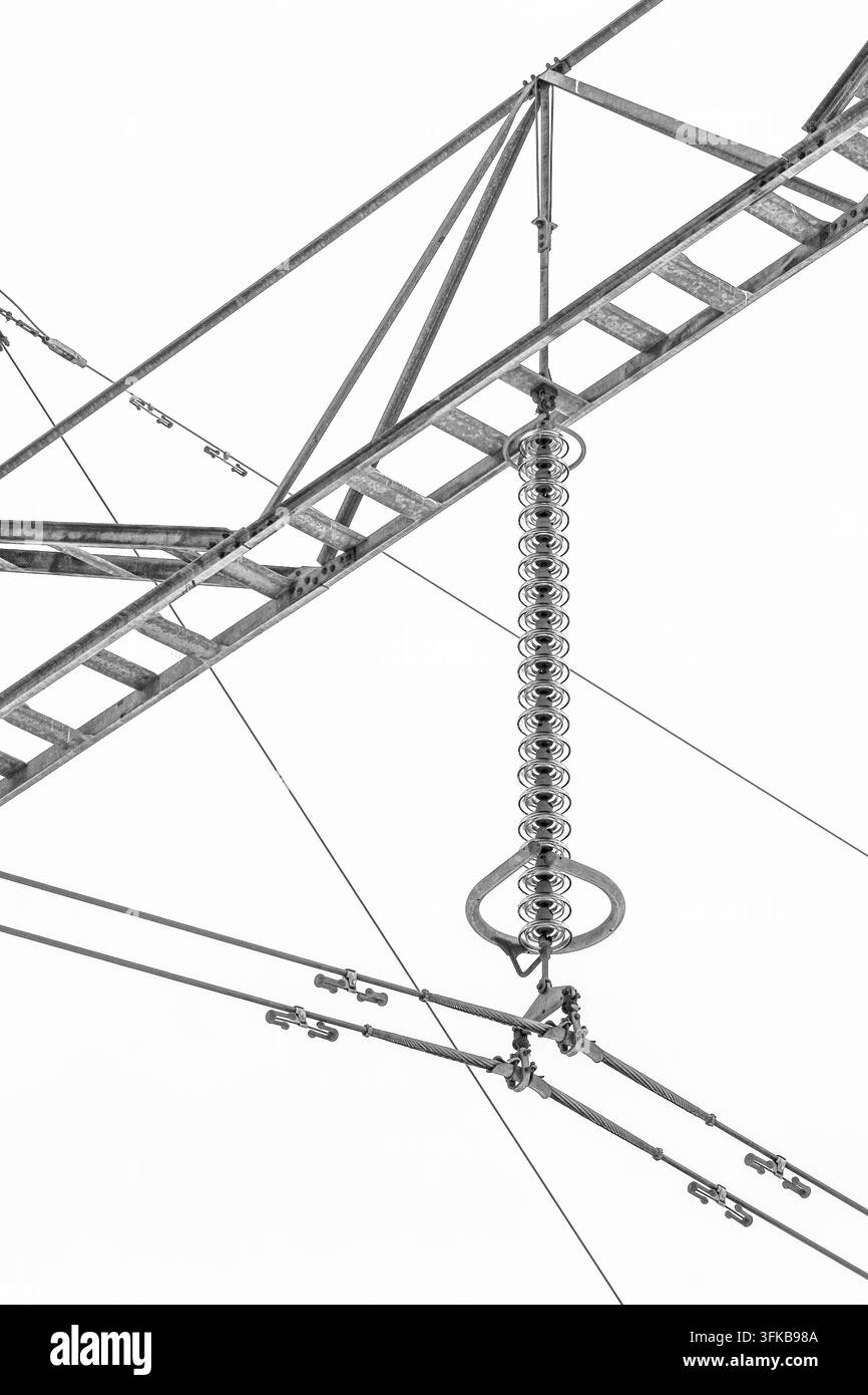 Linea ad alta tensione con catena di isolatori in vetro e struttura metallica di trasmissione fotografata contro un cielo nuvoloso luminoso. Foto Stock