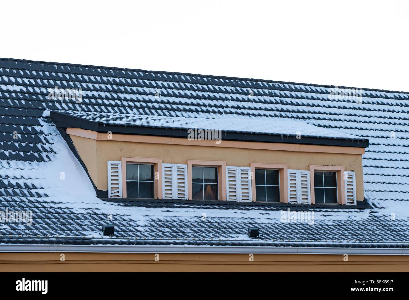 Villa gialla coperta di neve con abbaini sul tetto, giorno d'inverno Foto Stock