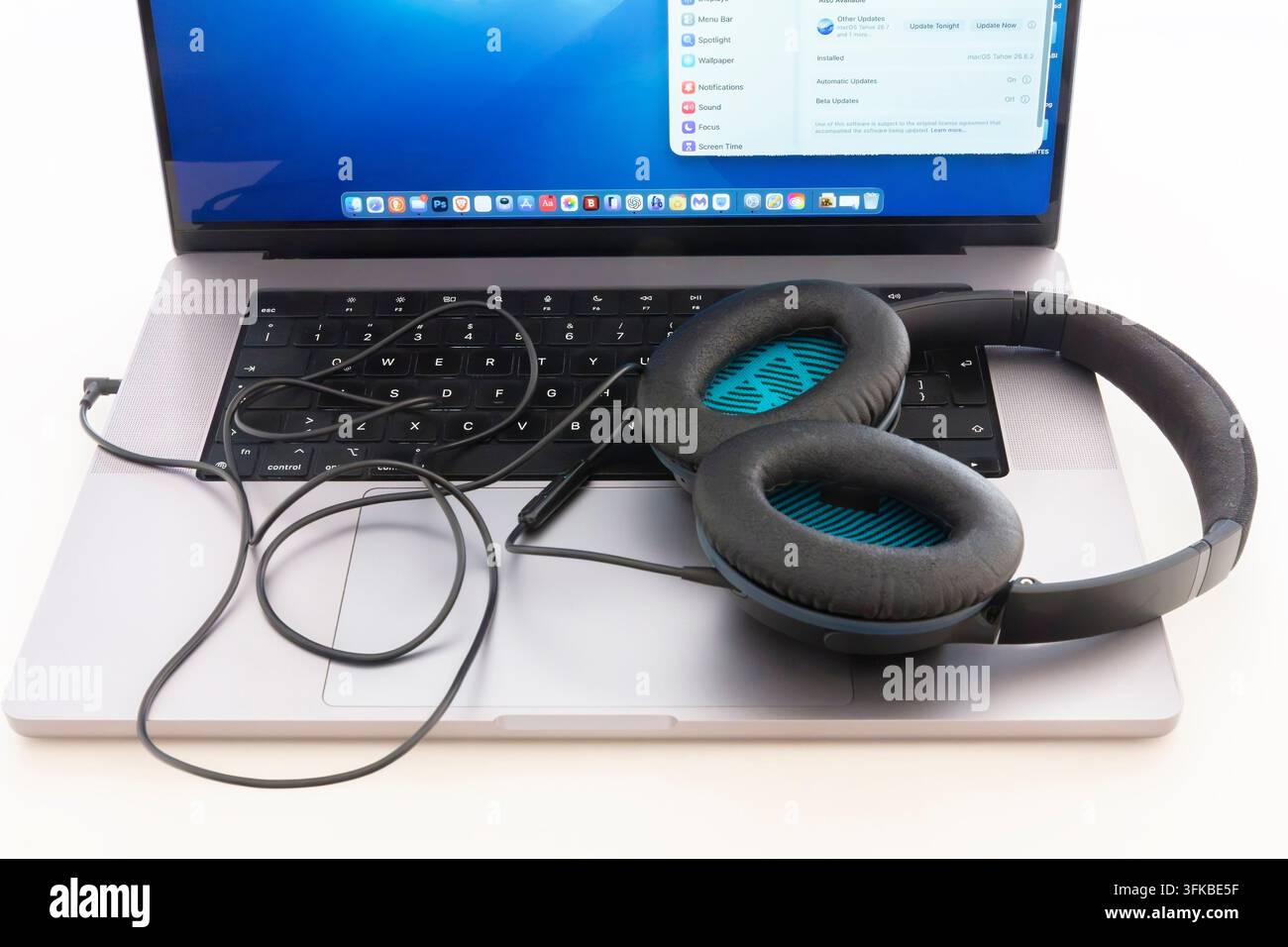 Un paio di cuffie cablate collegate a un computer portatile Apple MacBook Pro. L'immagine illustra l'audio personale, l'ascolto di musica, la tecnologia digitale Foto Stock
