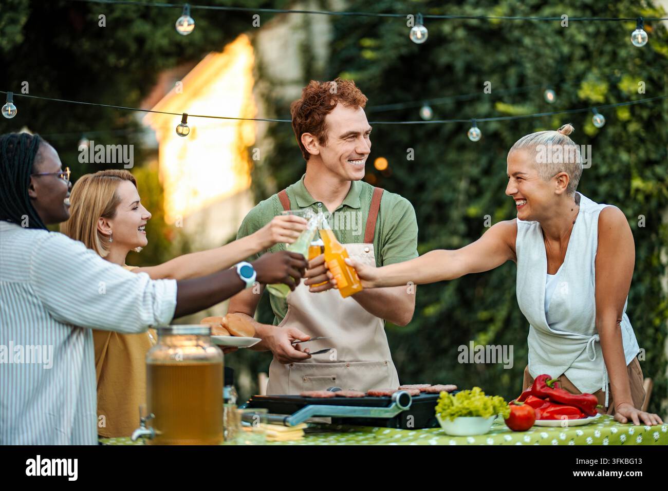 Adunanza gioiosa a un barbecue nel cortile con amici che celebrano buon cibo e risate Foto Stock