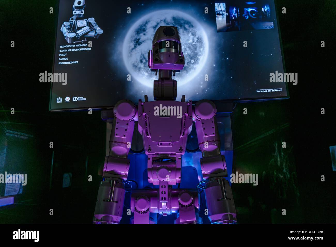 Robotto futuristico in mostra in un museo buio con uno sfondo di schermo lunare. Mosca, Russia - 17 luglio 2026 Foto Stock