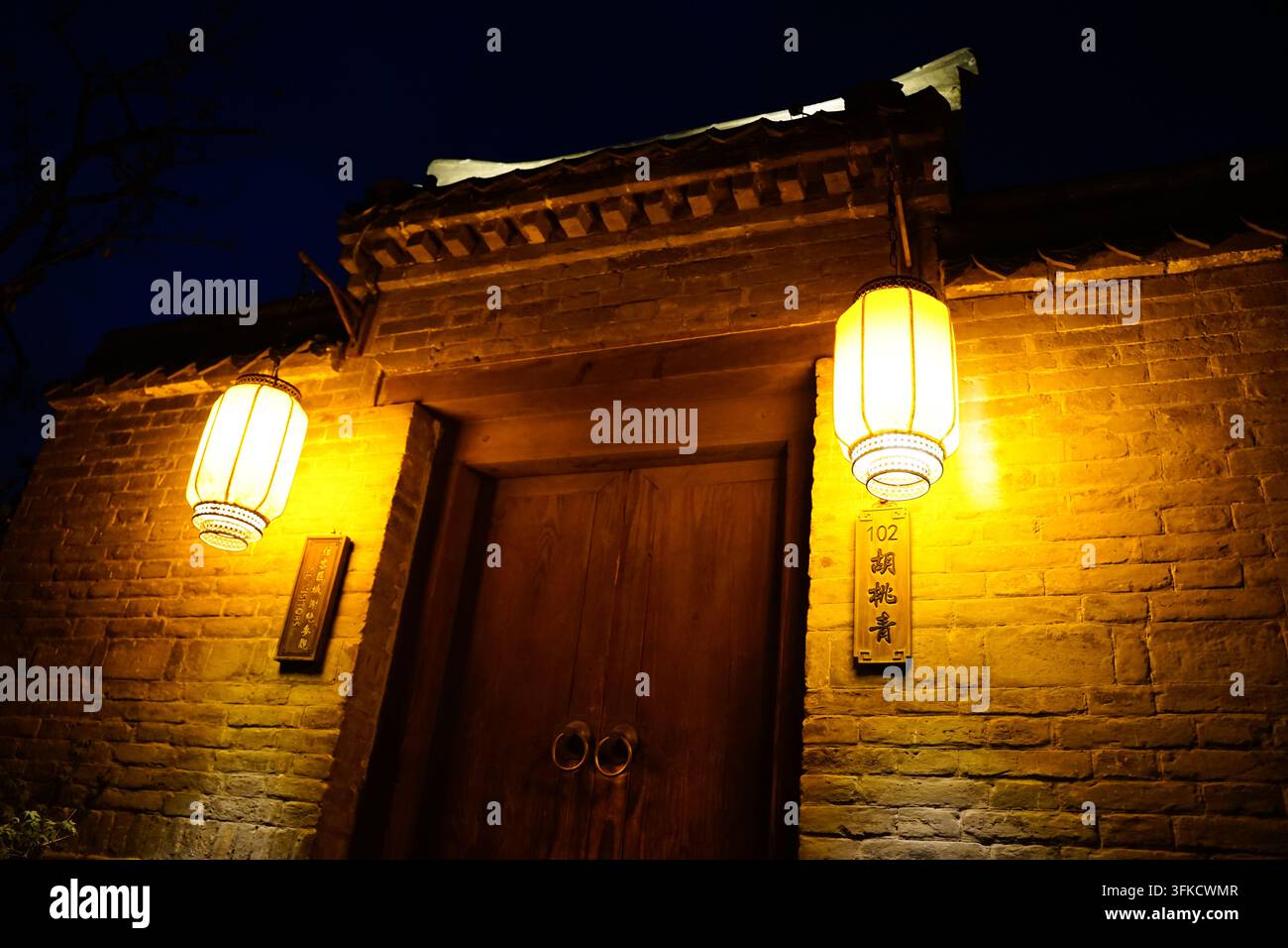 Lanterne gialle calde appese all'ingresso di un'antica magione di notte Foto Stock