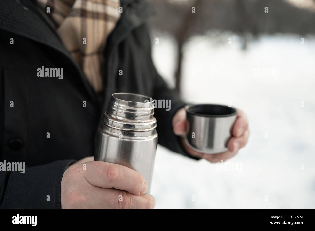 Termos aperto e tazza all'aperto in un parco invernale innevato Foto Stock