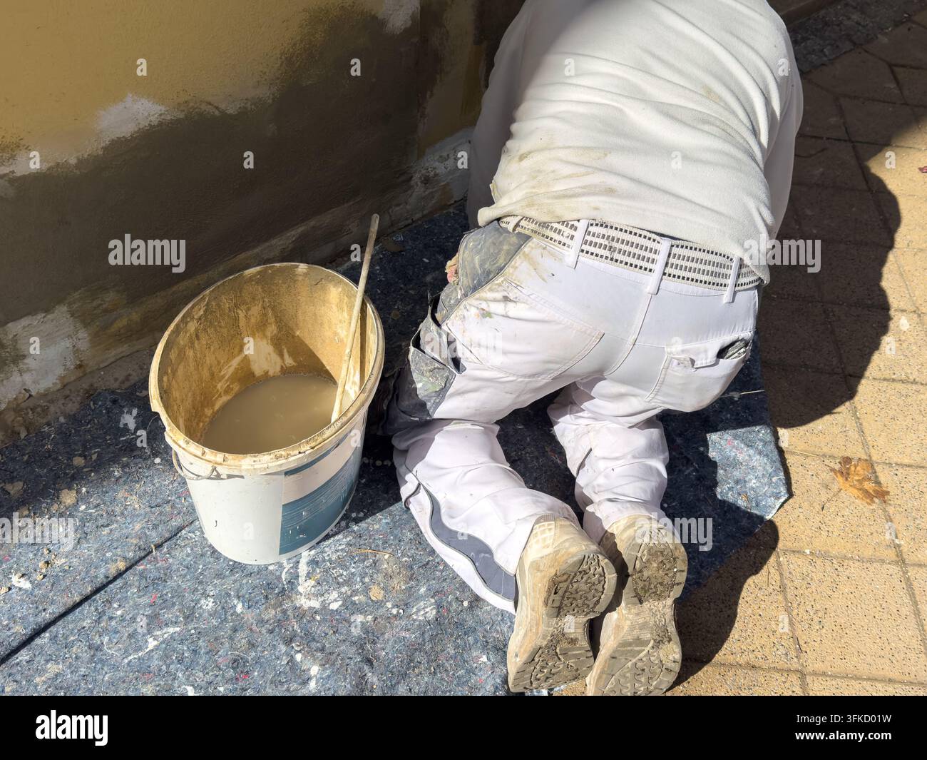 Operaio edile che utilizza una cazzuola per applicare intonaco ruvido sulla parete esterna di una casa. L'artigiano esperto sta lavorando sulla superficie come parte Foto Stock