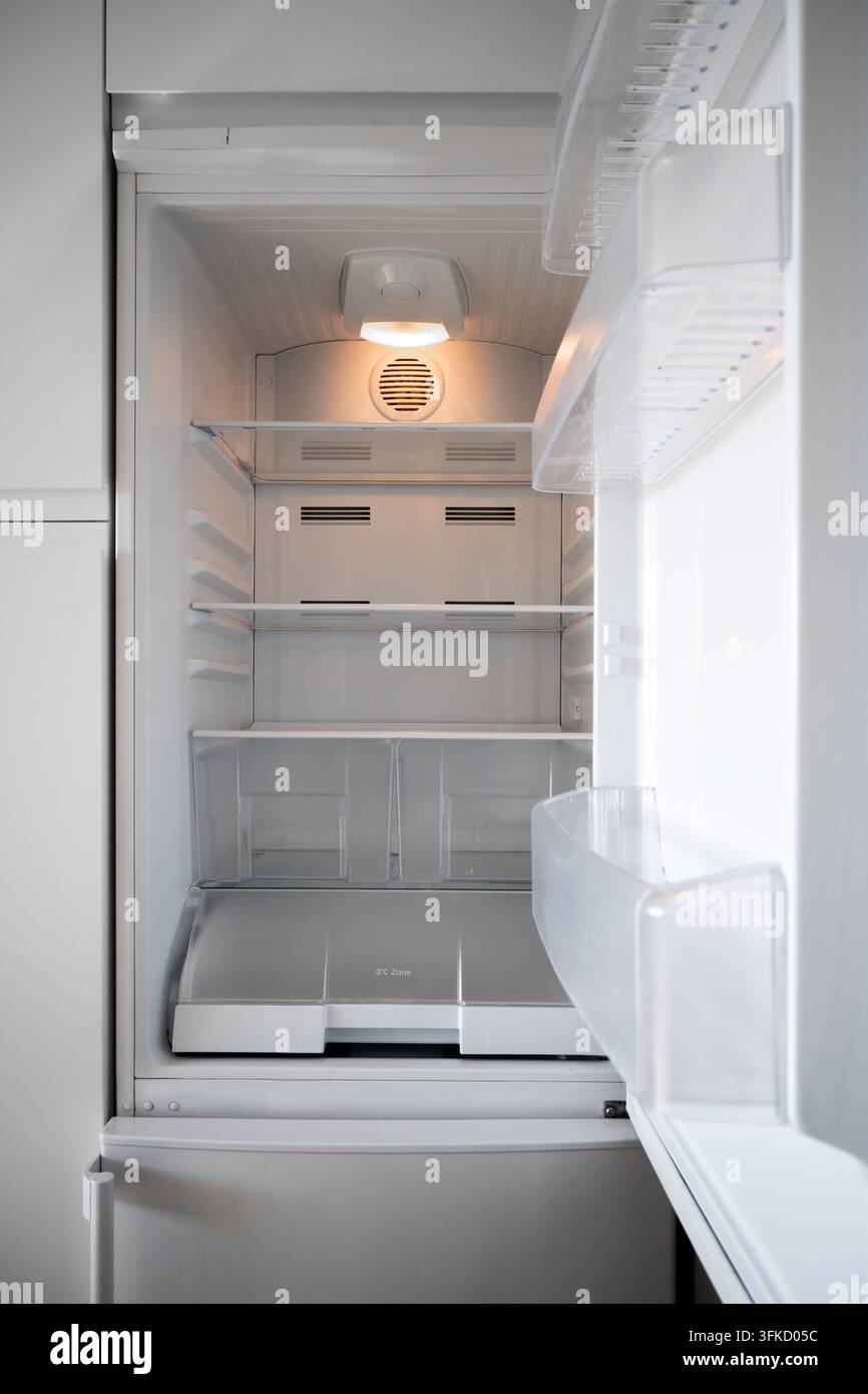 Vista interna di un frigorifero aperto e vuoto con ripiani e cassetti puliti, che rappresenta la carenza di cibo, la spesa, la pulizia o l'organizzazione domestica Foto Stock