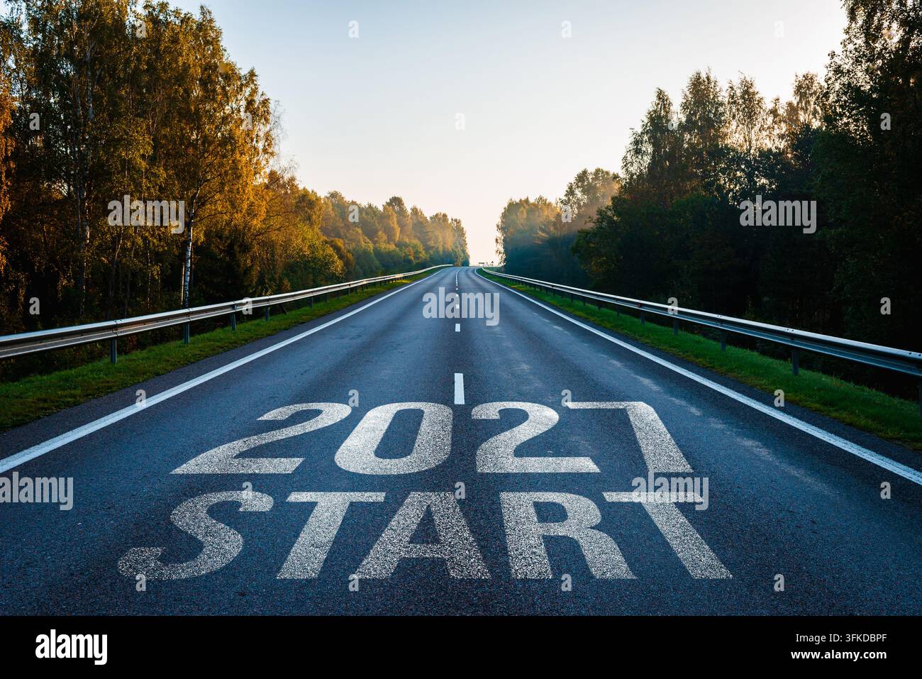 Autostrada asfaltata tra i boschi con il testo "Inizio 2027" dipinto sull'asfalto per la pianificazione futura e gli obiettivi. Foto Stock