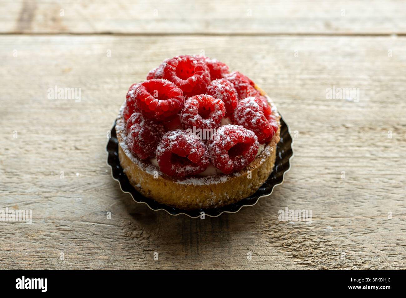 Torta di lamponi con zucchero a velo su tavolo rustico Foto Stock