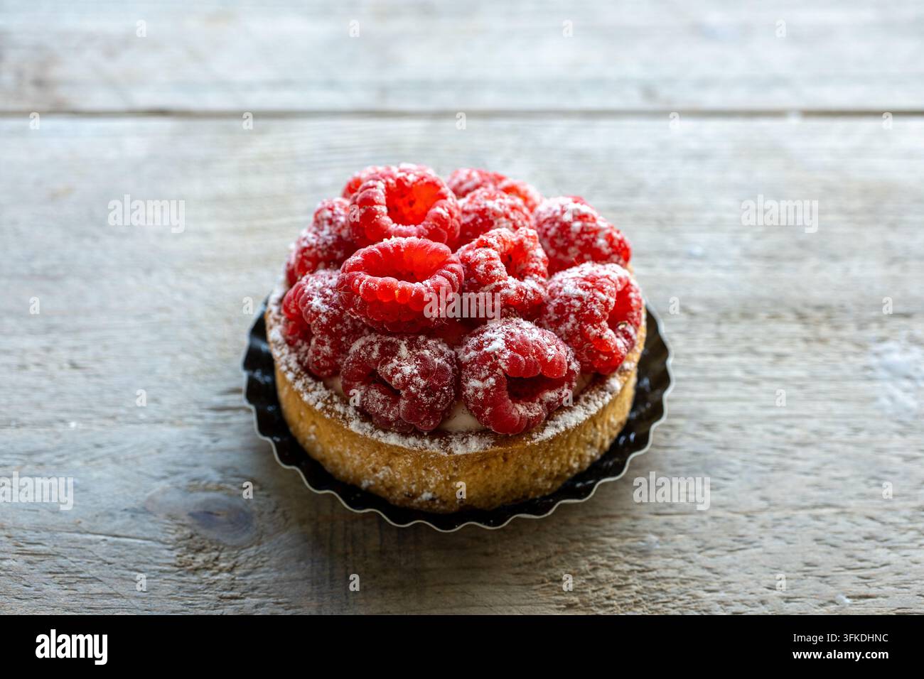 Torta di lamponi con zucchero a velo su tavolo rustico Foto Stock
