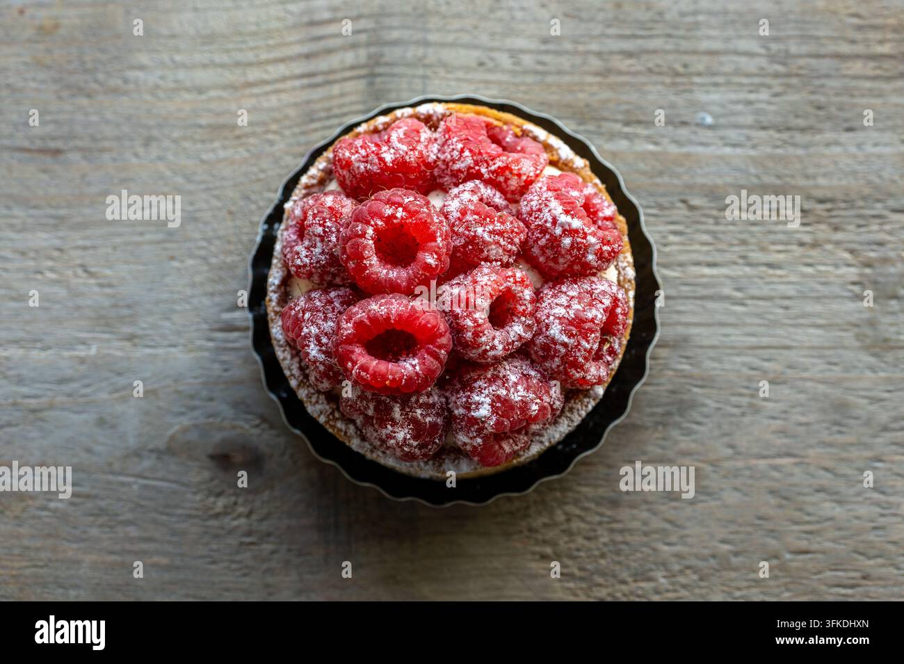 Torta di lamponi con zucchero a velo su tavolo rustico Foto Stock