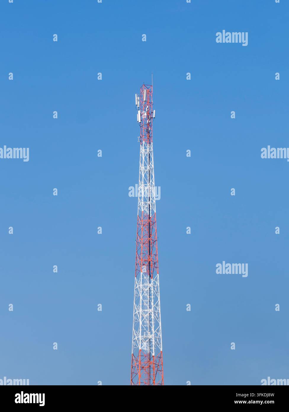 Torre di comunicazione rossa e bianca contro un cielo blu, che rappresenta la comunicazione senza fili, l'infrastruttura di trasmissione, la tecnologia e la rete Foto Stock